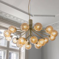 Gold chandelier with textured glass orbs, featuring a sleek design and warm lighting for a modern touch.