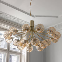Elegant gold chandelier with textured amber glass globes, featuring intricate bubble patterns for a stylish touch.