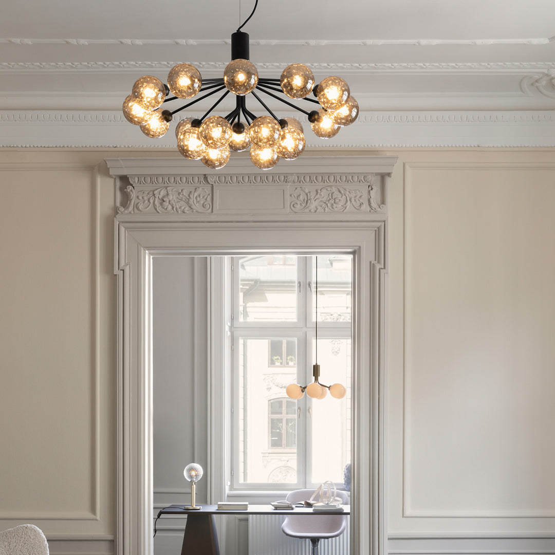 Modern black chandelier with multiple golden glass bulbs, enhancing chic and minimalist decor.