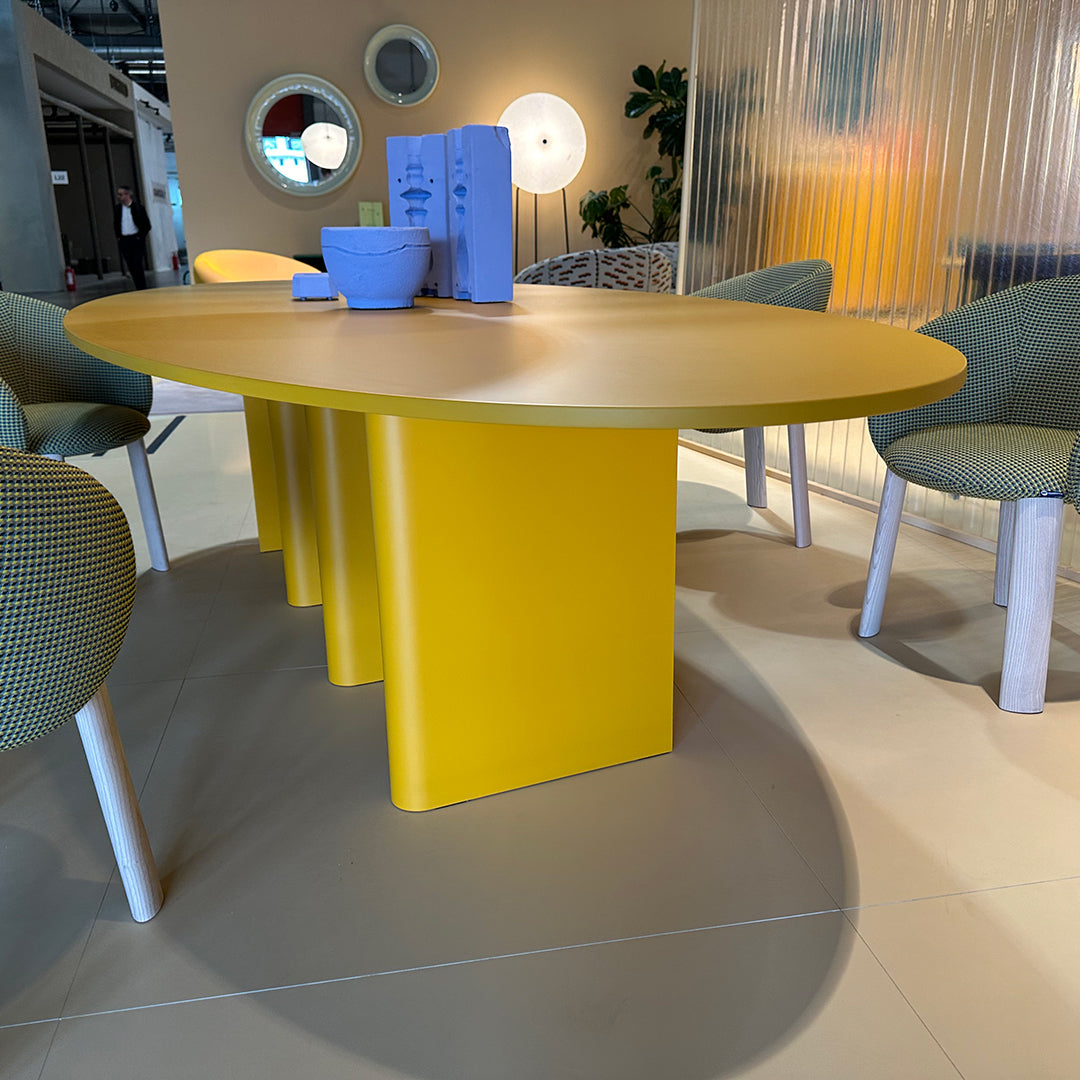Stylish oval yellow dining table with light green patterned chairs in a modern setting. Bright and inviting design.