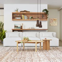 Luxurious white textured couch with earthy wood accents and a warm-toned patterned area rug. Modern minimalist decor.