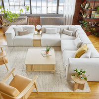 Lush white sectional sofa with light wood accents and mustard yellow pillows in a bright, airy room.