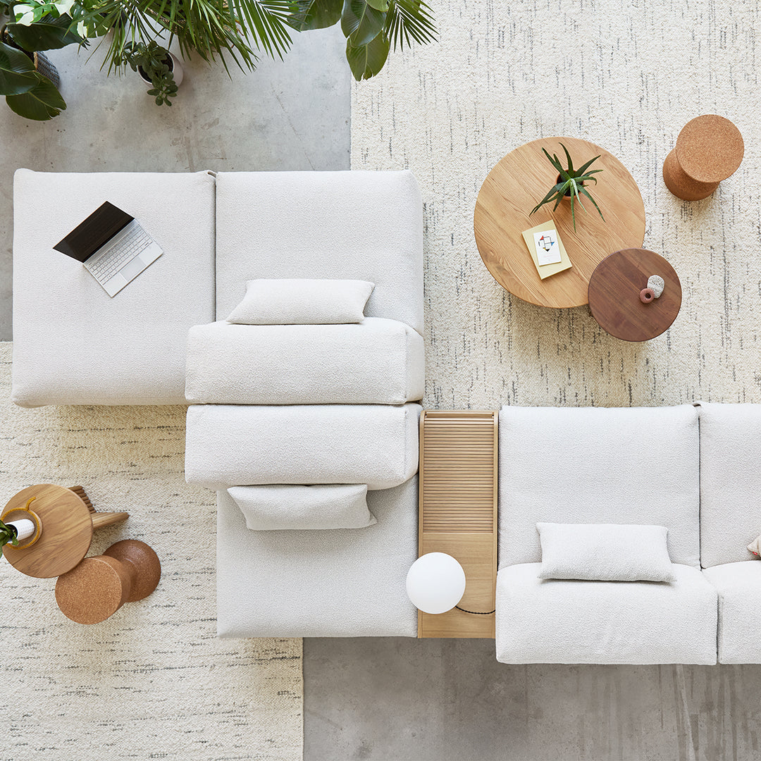 Soft white sofa with textured cushions, natural wood table, and earthy tones of a rug and decorative elements.