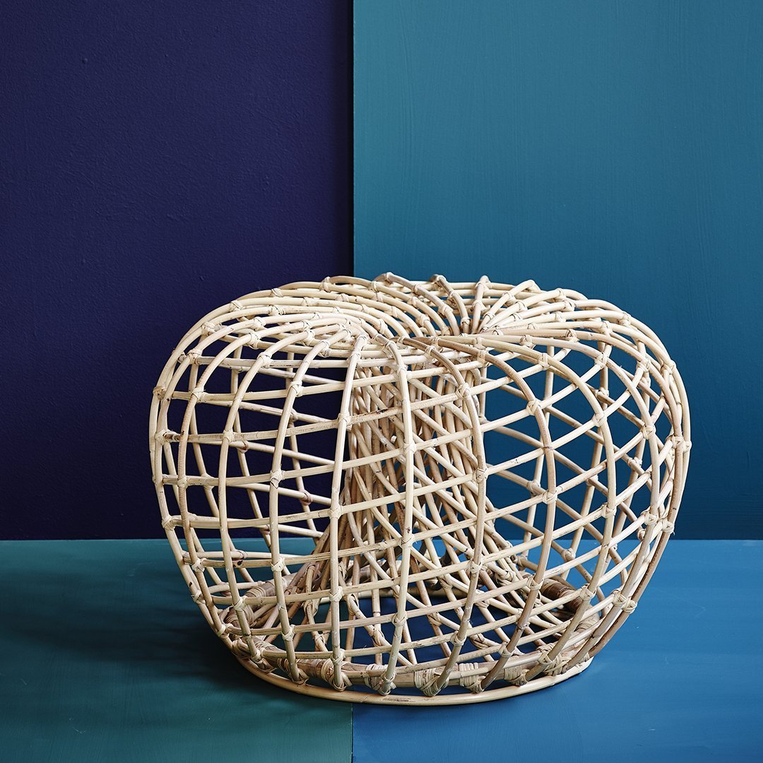 Natural woven rattan basket in an open, circular design against contrasting deep blue and purple backgrounds.