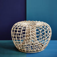 Natural woven rattan basket in an open, circular design against contrasting deep blue and purple backgrounds.