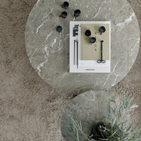 Gray marble table with a magazine and black decorative items, featuring soft earthy tones for a modern aesthetic.