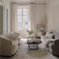 Modern living room with neutral tones, soft textures, and minimalistic patterns on cushions and rugs.