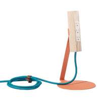 Modern lamp with a wood finish, coral base, and vibrant turquoise cord. Sleek, minimalist design with bold colors.