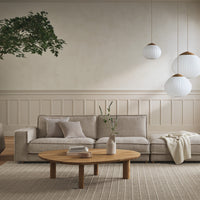 Light beige sofa with a soft textured pattern, complemented by a round wooden coffee table and neutral tones in decor.