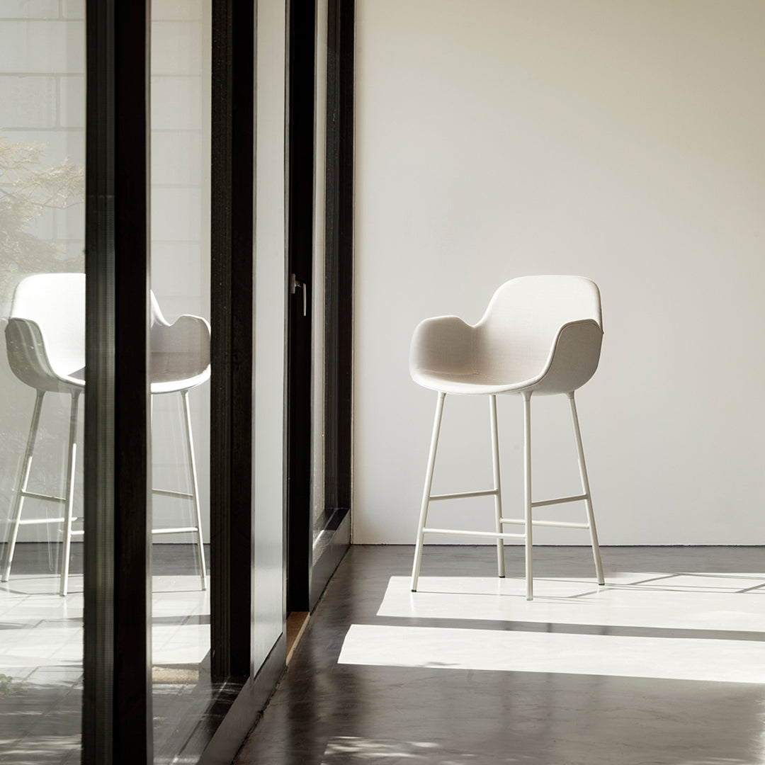Stylish light gray chair with smooth curves and minimalist design, set against a bright, modern interior.