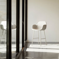 Stylish light gray chair with smooth curves and minimalist design, set against a bright, modern interior.