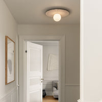 Round ceiling light with a textured white shade and warm glow, complementing neutral walls and wooden floor.