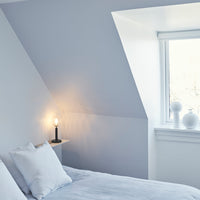Soft blue walls with minimalist white decor and light gray bedding create a serene bedroom ambiance.