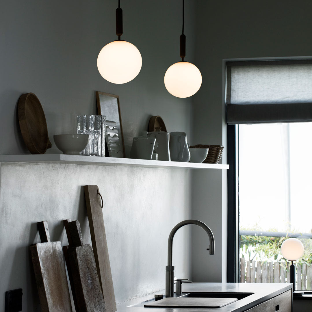 Elegant white spherical pendant lights against a muted gray wall, complementing a minimalist kitchen decor.