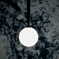 Minimalist white orb pendant light against a textured dark blue wall, highlighting modern design.