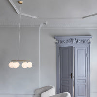 Elegant white globe pendant light against a soft gray wall and a pale lavender door, adding a modern touch to decor.