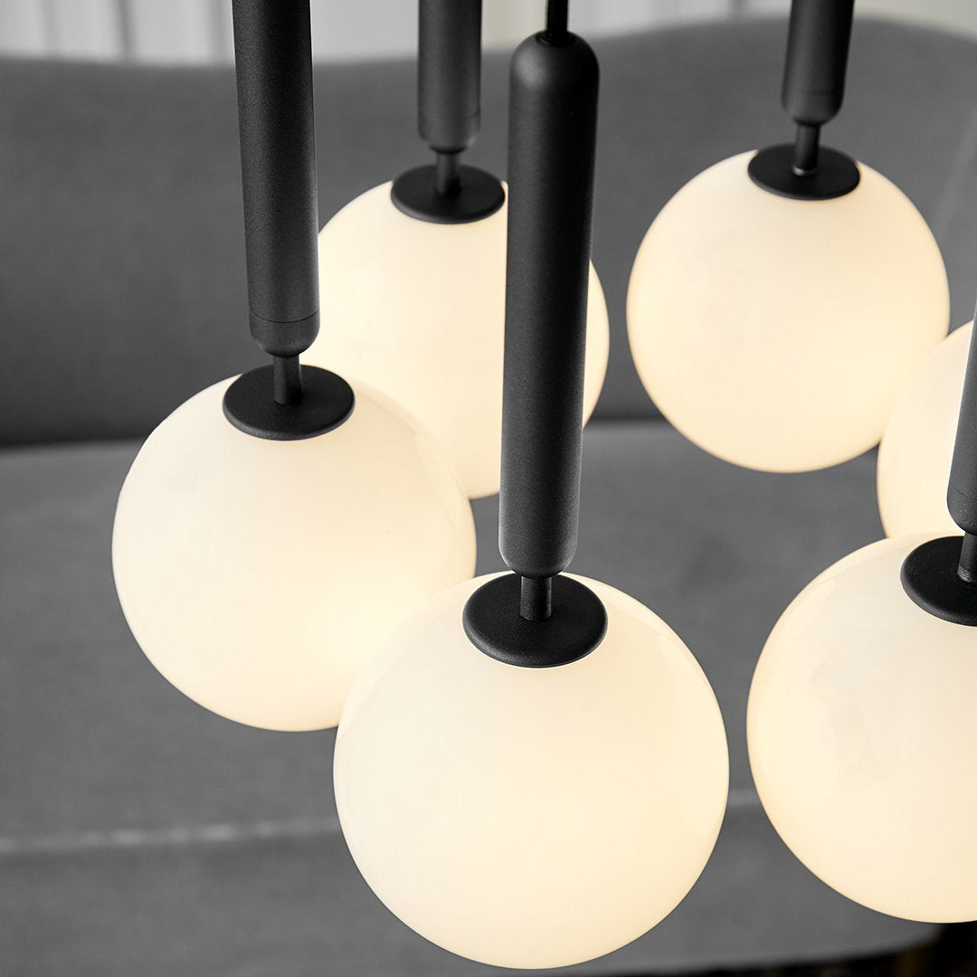 Modern chandelier with black accents and frosted white glass orbs, creating a sleek and contemporary look.