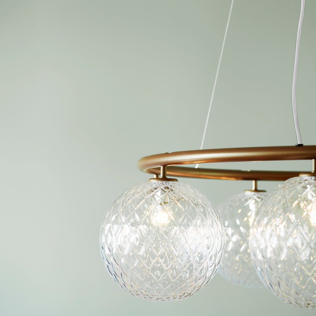 Elegant gold-finished pendant light with clear crystal globes and intricate diamond-patterned glass.