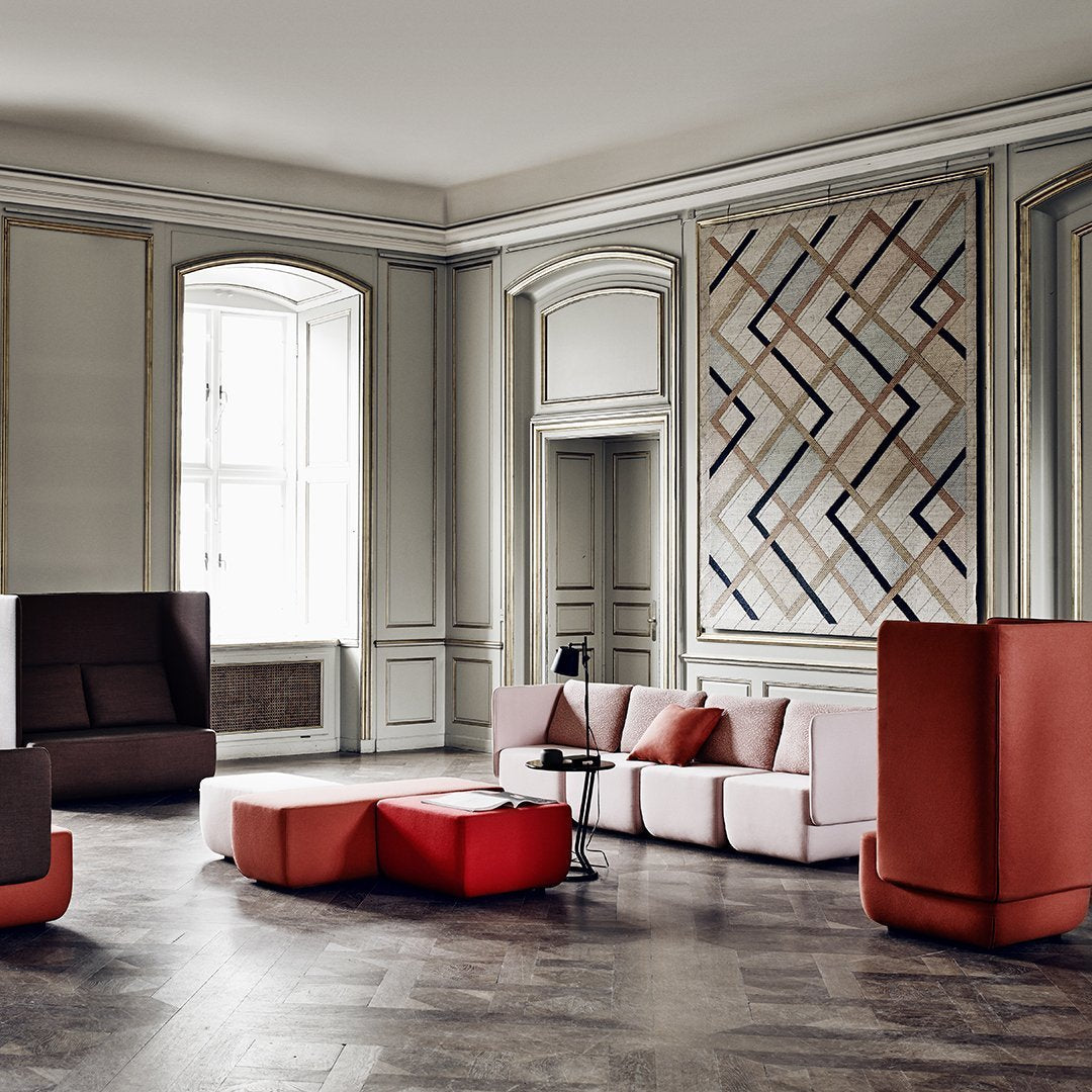Modern seating in soft pink, deep red, and earthy brown tones, featuring geometric patterns and textures.