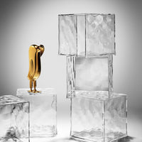 Gold decorative figure atop textured clear glass blocks with geometric patterns, creating a modern and elegant look.
