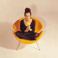Vibrant orange chair with soft, rounded edges and sleek silver legs, set against a neutral backdrop.