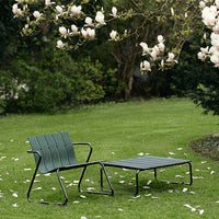 Dark green striped patio chairs on a grassy lawn, surrounded by blooming magnolia flowers.