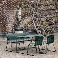 Green striped outdoor dining set with sleek black metal frames against a rustic brick backdrop.