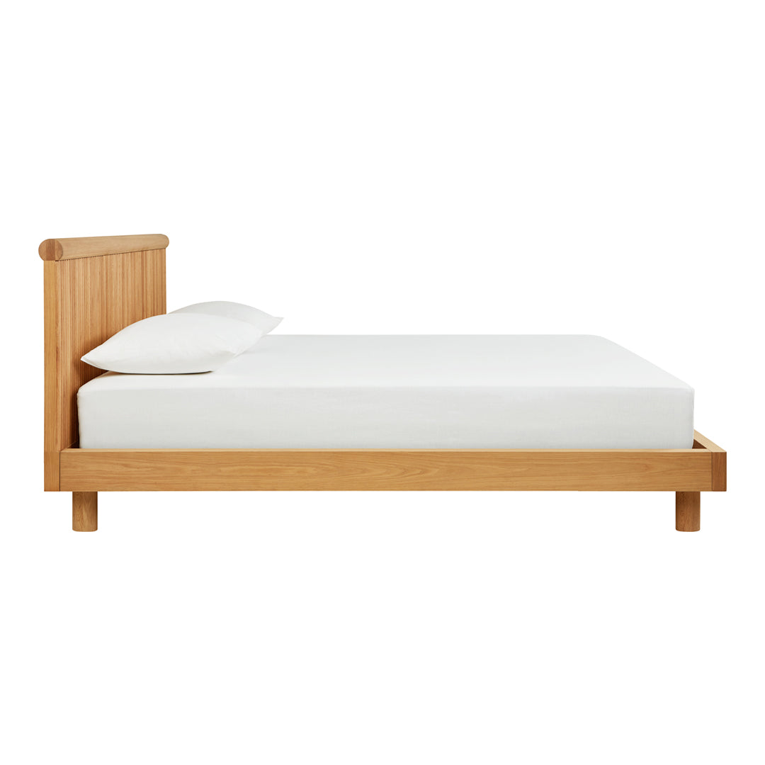 Natural wood bed frame with a light oak finish and a smooth, minimalist design. White mattress and pillows complete the look.