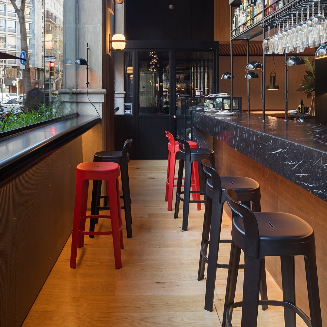Red and black bar stools against a sleek black marble counter and warm wooden tones in a modern café setting.