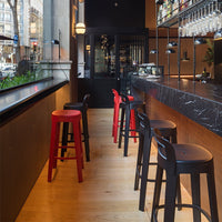 Red and black bar stools against a sleek black marble counter and warm wooden tones in a modern café setting.