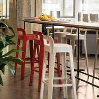 Colorful bar stools in red and white with sleek modern design, set against a contemporary office backdrop.