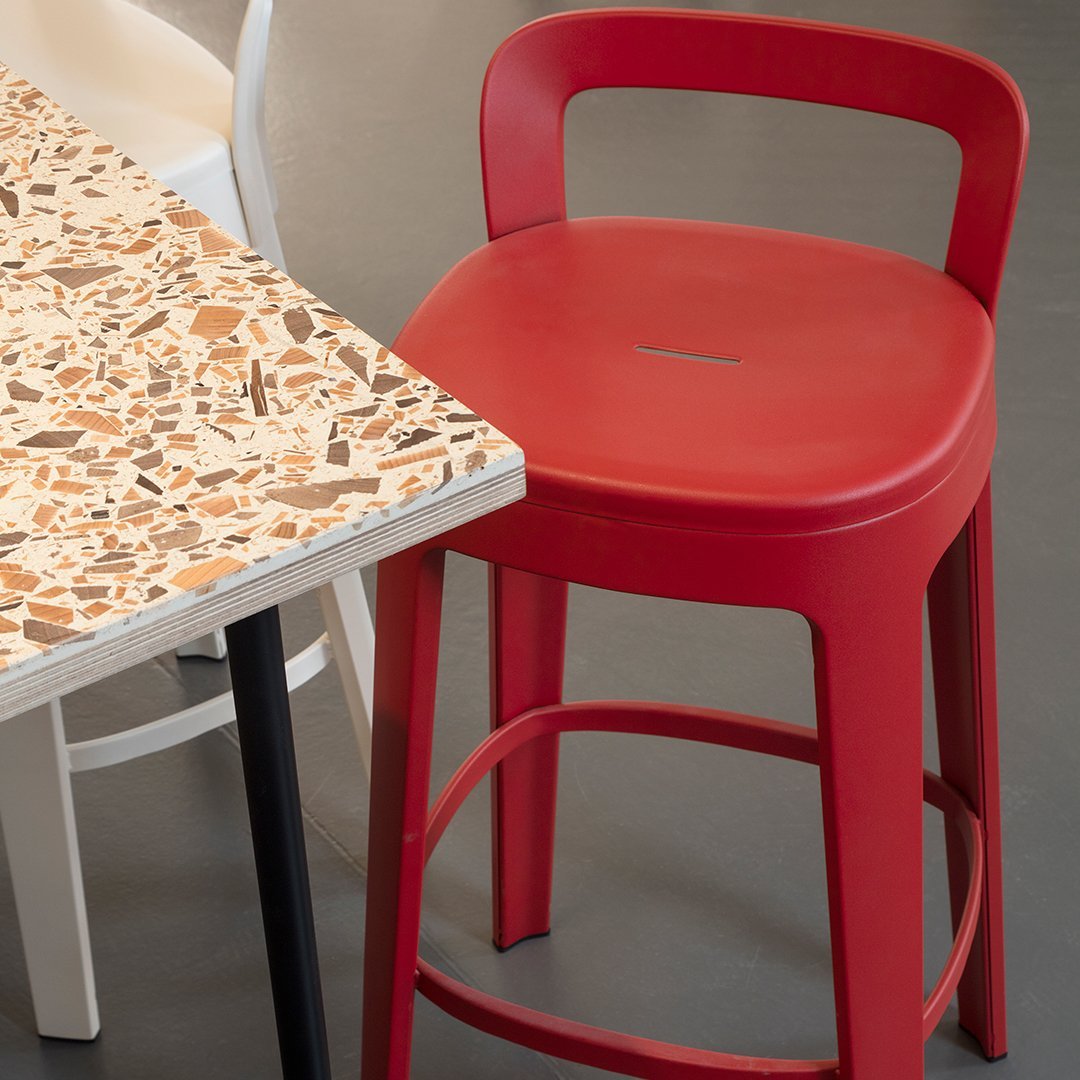 Vibrant red metal stool paired with a neutral terrazzo-patterned tabletop. Modern and stylish decor.