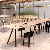 Modern workspace featuring a light wood table and sleek black chairs on a polished white floor. Soft natural lighting accents.