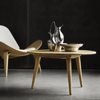 Light natural wood coffee table with a smooth finish, paired with sleek metallic decor, set against a dark backdrop.