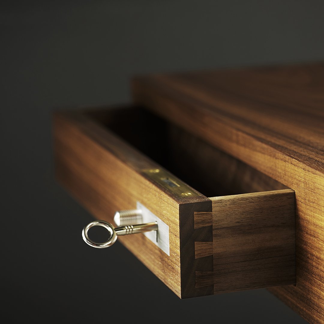 Close-up of a wooden drawer with a rich dark brown finish and subtle grain patterns. Silver keyhole accent.