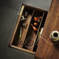 Open wooden drawer featuring rich brown tones, brass accents, and pops of red and yellow in organizing tools.