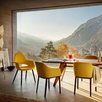 Yellow modern chairs surrounding a sleek wooden table, with a natural landscape background of mountains and trees.