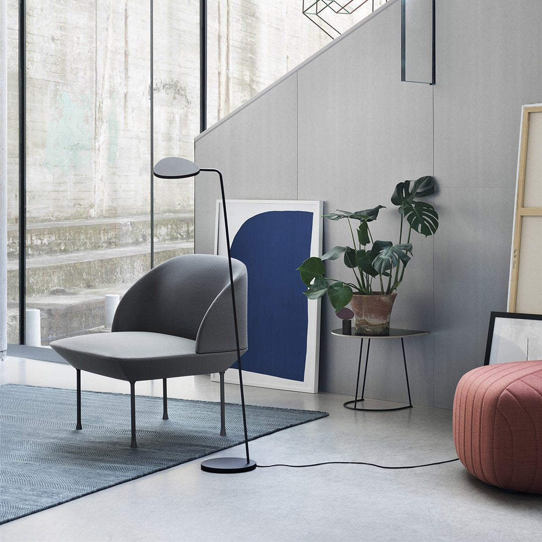 Modern gray and light gray chair with a sleek design, paired with a geometric blue wall art and earthy-toned accents.