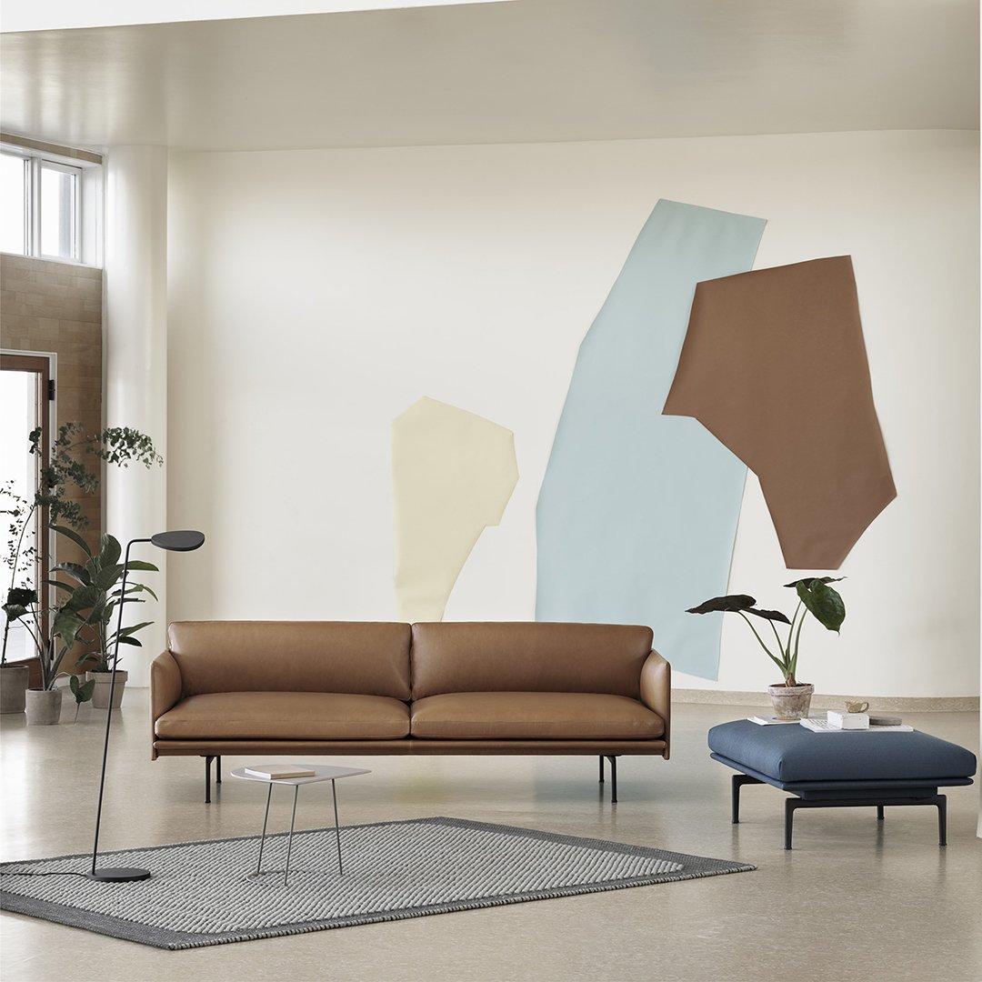 Modern living room featuring a brown leather sofa, muted pastel wall colors, and a textured gray rug.