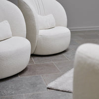 Soft white boucle fabric armchairs on gray tiled floor, creating a modern and cozy atmosphere.