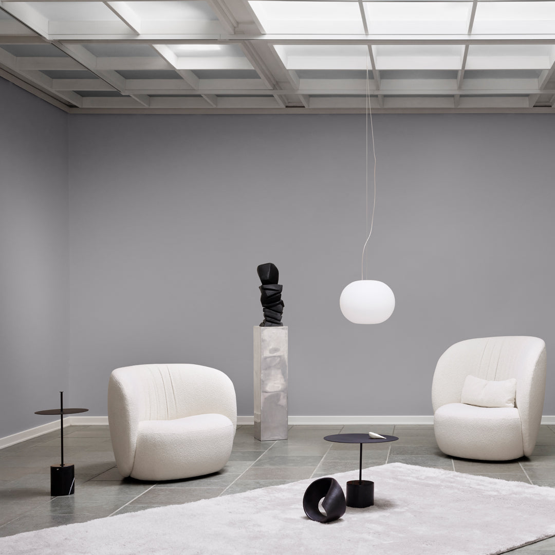 Modern white chairs on gray backdrop with soft neutral accents and sleek black decor elements.