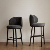 Two sleek bar stools in textured charcoal gray, featuring curved backs and contrasting black and dark wood legs.