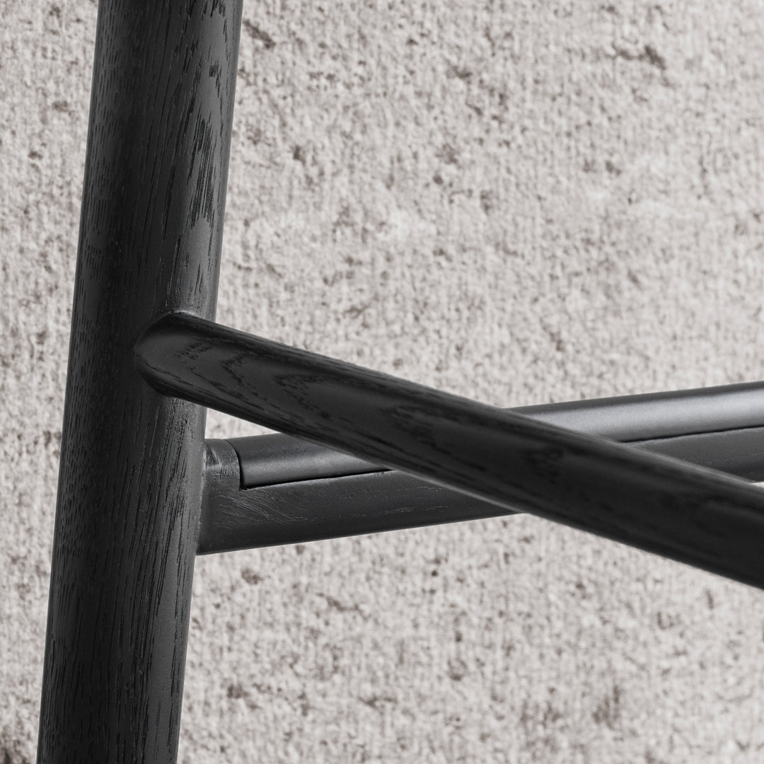 Black wooden chair with a sleek, modern design, showcasing smooth lines and a minimalist aesthetic against a light backdrop.