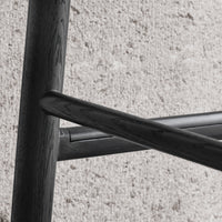 Black wooden chair with a sleek, modern design, showcasing smooth lines and a minimalist aesthetic against a light backdrop.