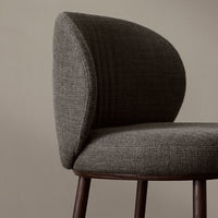 Curved gray upholstered chair with subtle texture and rich brown wooden legs against a neutral background.