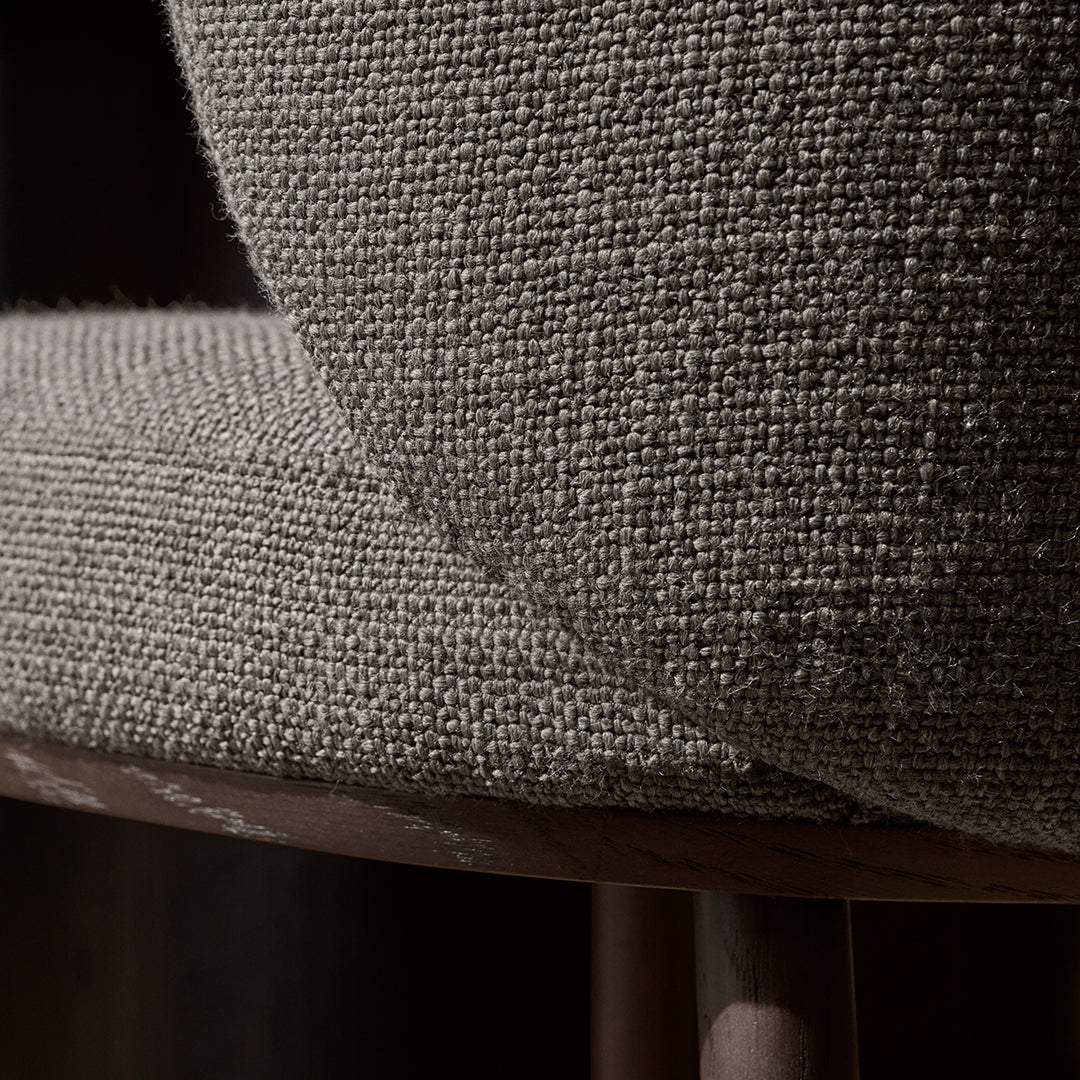 Close-up of a textured gray fabric on a chair, highlighting its woven pattern and neutral tones.