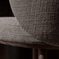 Close-up of a textured gray fabric on a chair, highlighting its woven pattern and neutral tones.