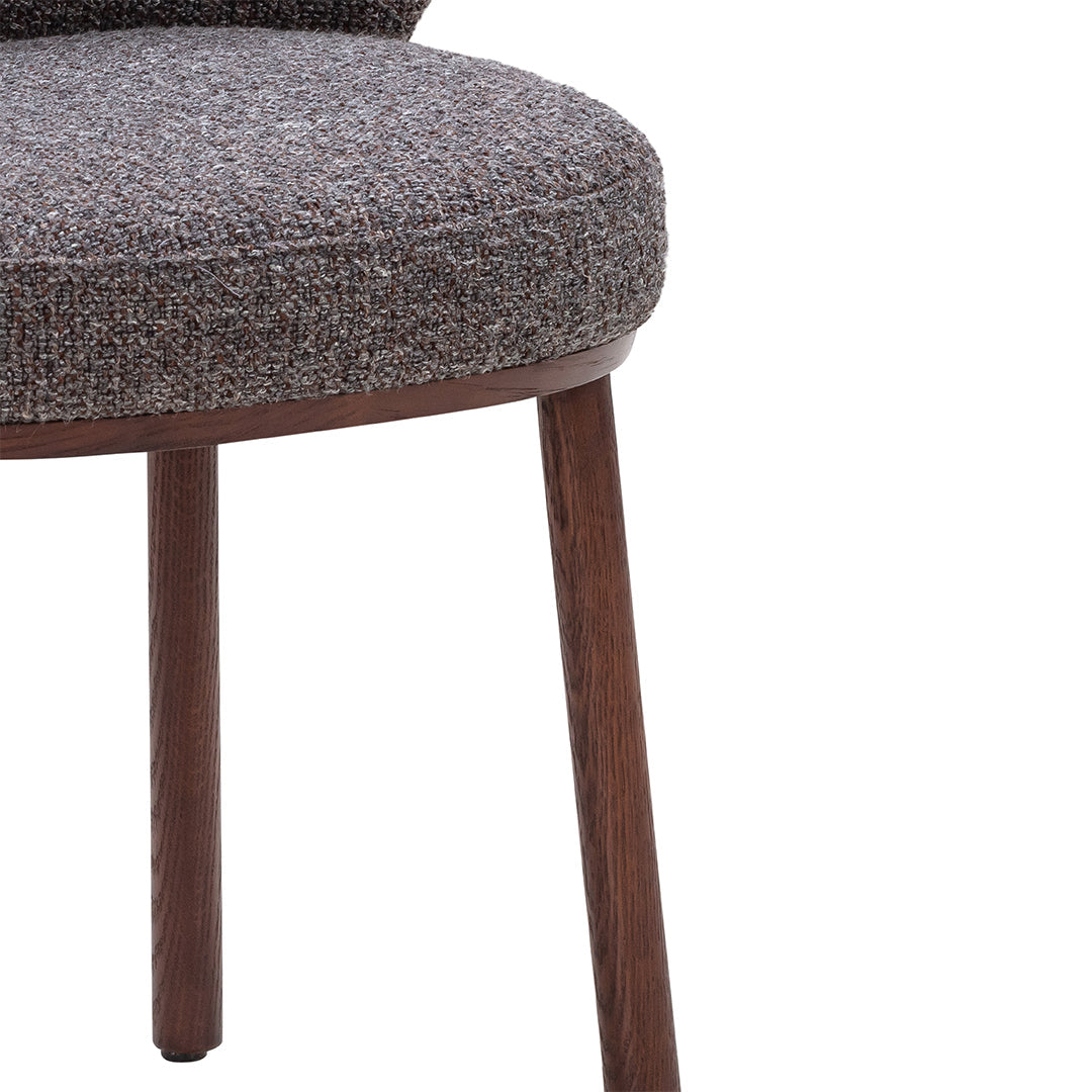 Brown textured upholstery on a rounded chair seat, with wooden legs adding a natural finish.