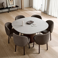 Round marble dining table with gray upholstered chairs, set on light wooden floor in a modern interior.