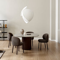 Contemporary dining table with a smooth gray top and dark wood base, complemented by brown textured chairs, minimalist design.